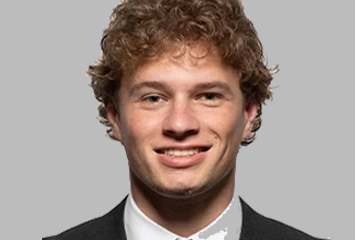 Bart - Fresh Legs Hockey School Head-and-shoulders portrait of a smiling man in a dark suit and white shirt against a gray background.